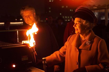 Queen Elizabeth II lights a beacon floating in the Thames as she travels by boat to the Millennium Dome at Greenwich. Earlier, she visited a shelter for homeless people and attended a service at Southwark Cathedral. (AP Photo by kind permission of the Pre